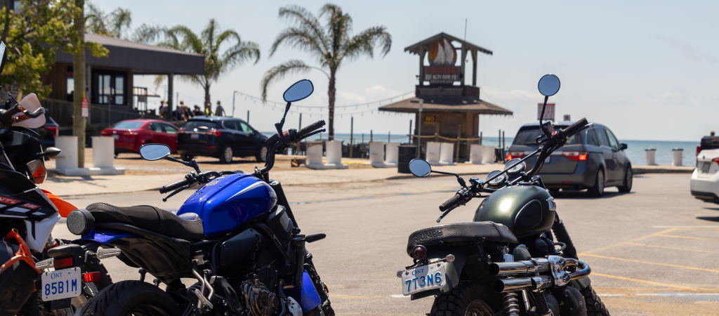 Motorcycles parked at beach, in front of Callahan's Beach House tiki bar with palm trees in the background.