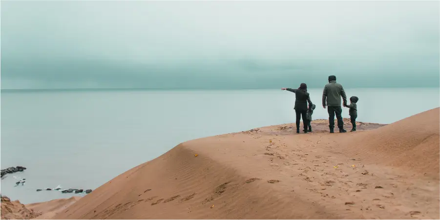 A family on a sand dune overlooking a lake
