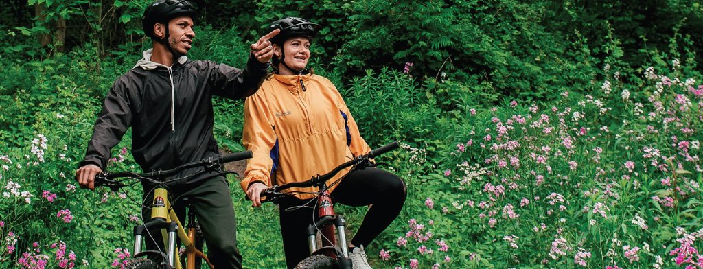 two adults on bikes, stopped in woodland trail
