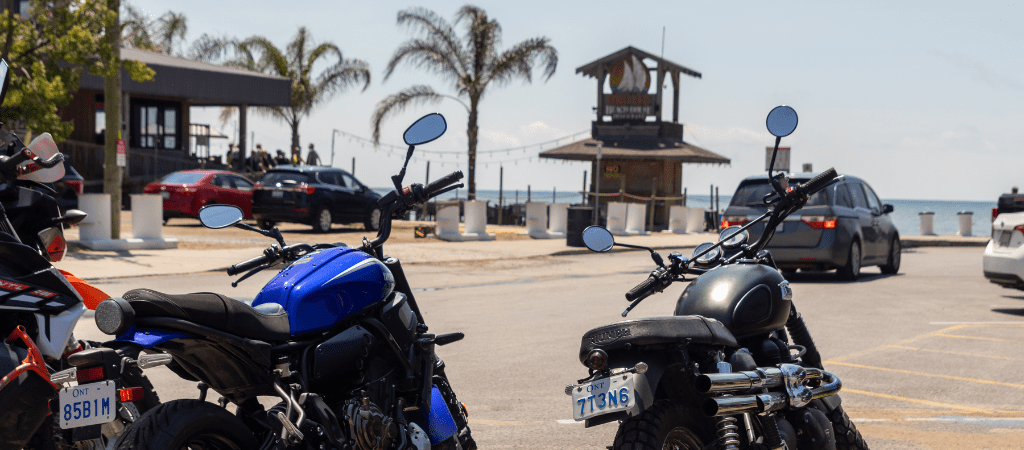 Motorcycles parked at beach, in front of Callahan's Beach House tiki bar with palm trees in the background.