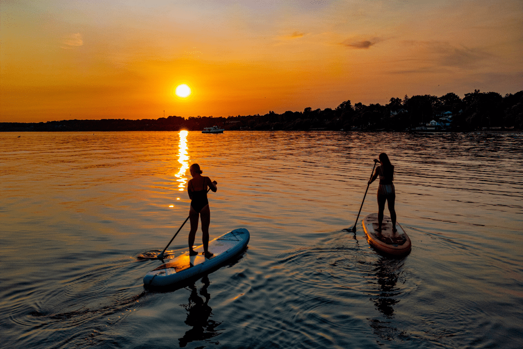 Paddle boarders on shoreline at sunset