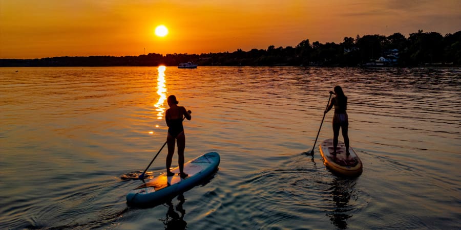 paddleboarders on a lake at sunset