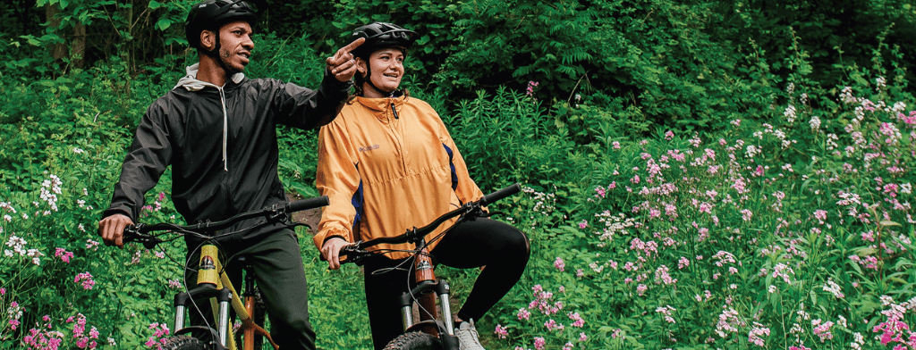 two adults on bikes, stopped in woodland trail