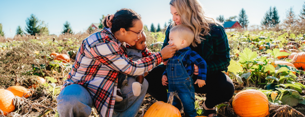 Two women in pumpkin field with children